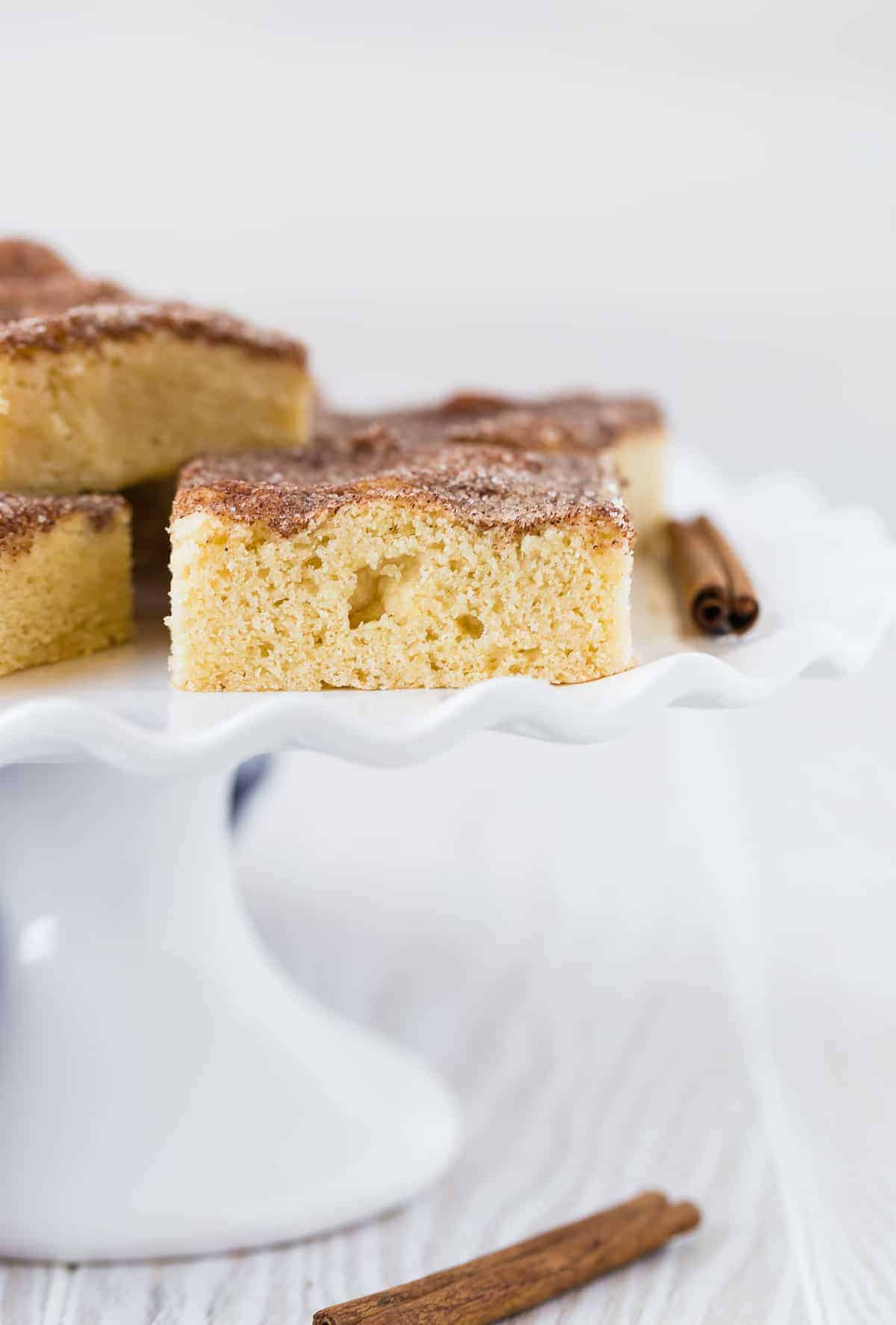 Cookie bar with cinnamon sugar topping, on a cake stand with others.