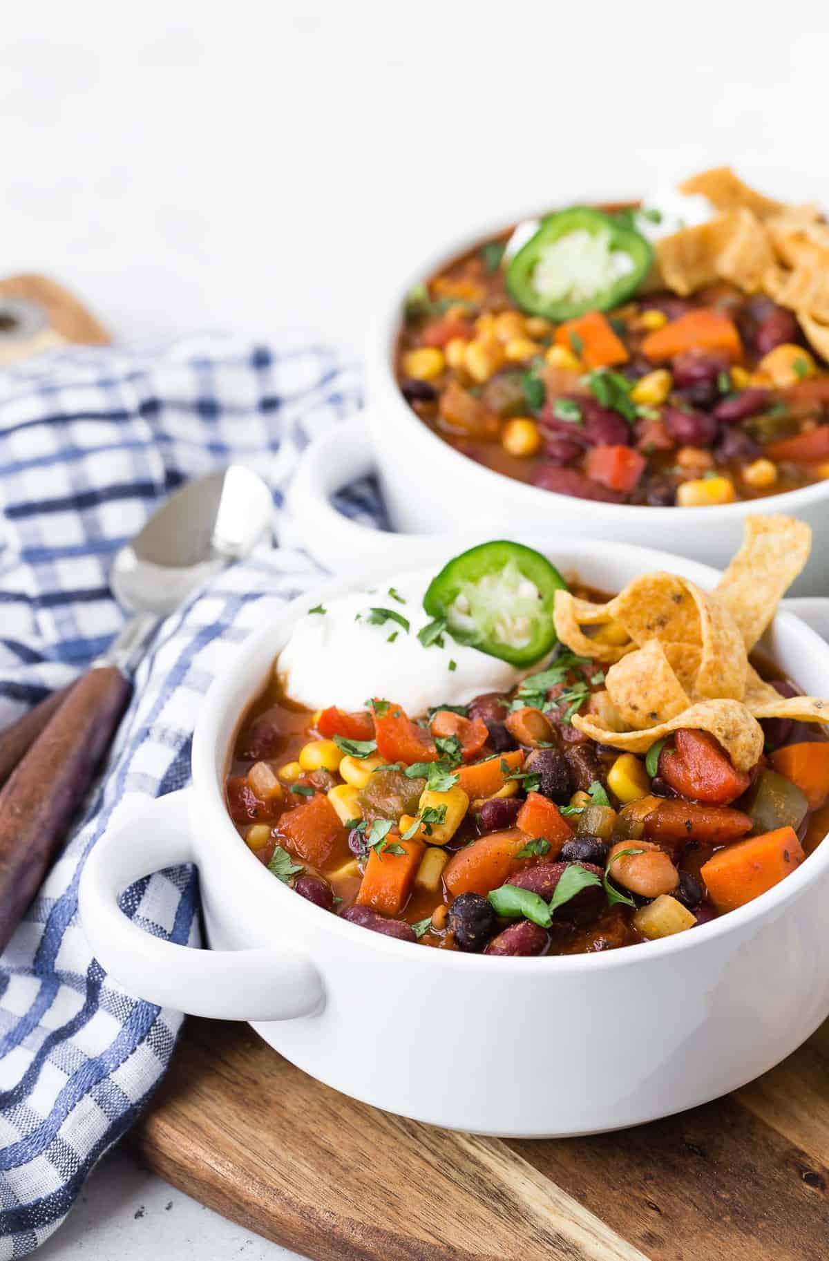 Two bowls of chili on a wooden surface.