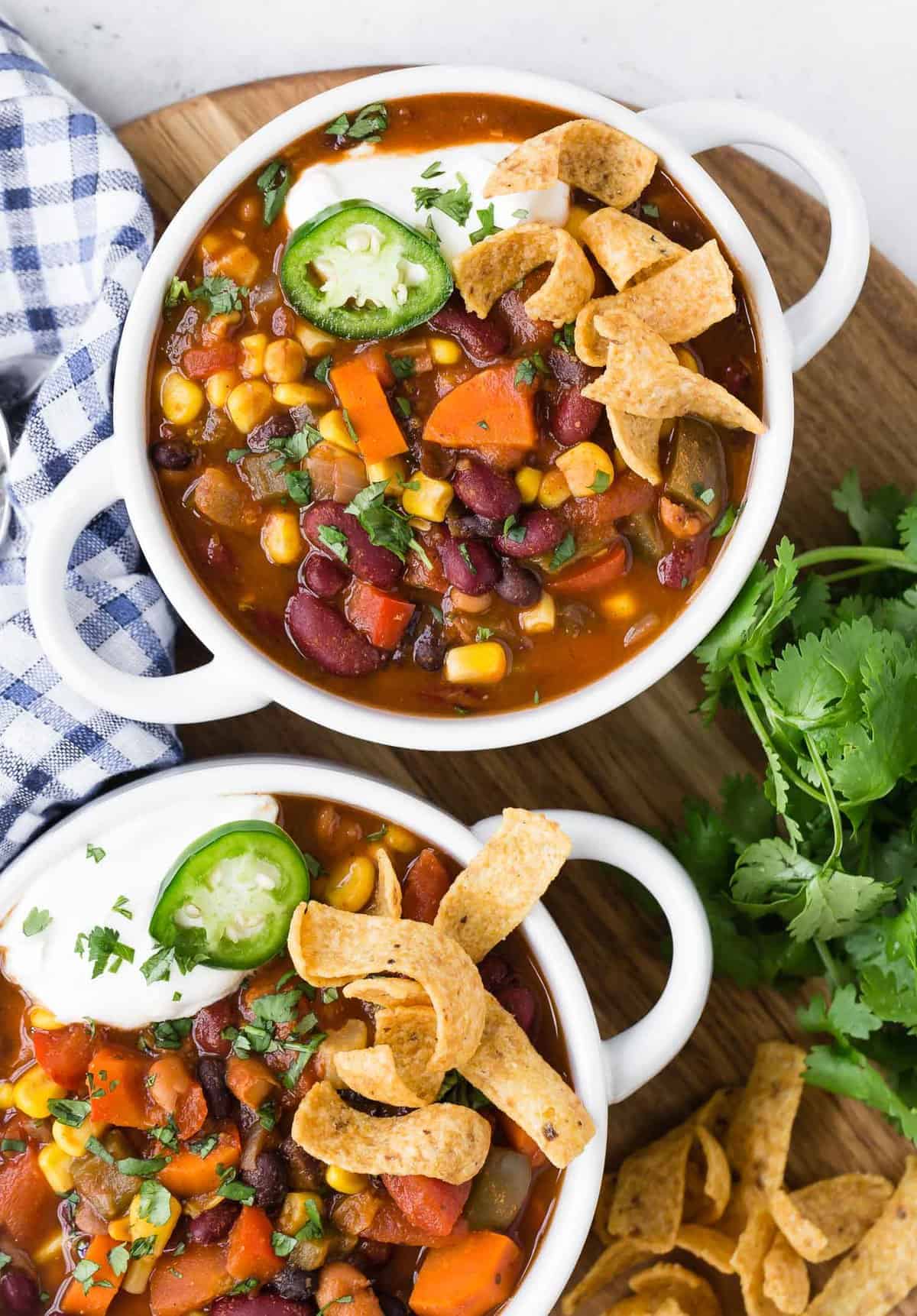 Overhead view of two white bowls with handles, filled with chili and toppings.