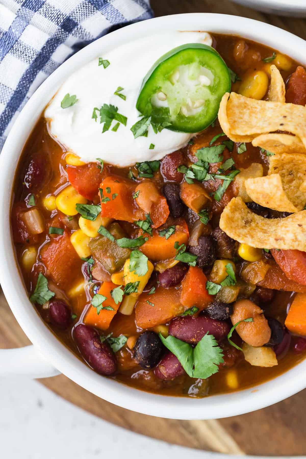 Overhead view of white bowl of vegetarian chili with toppings.