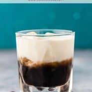 A short clear glass with a layered dark brown and white drink. Text overlay reads "white russian cocktail, rachelcooks.com"