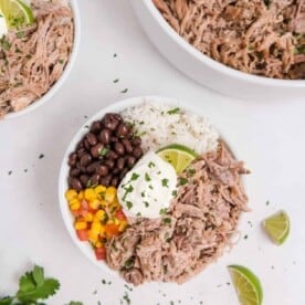 Pulled pork in a bowl with rice, black beans, corn and sour cream.