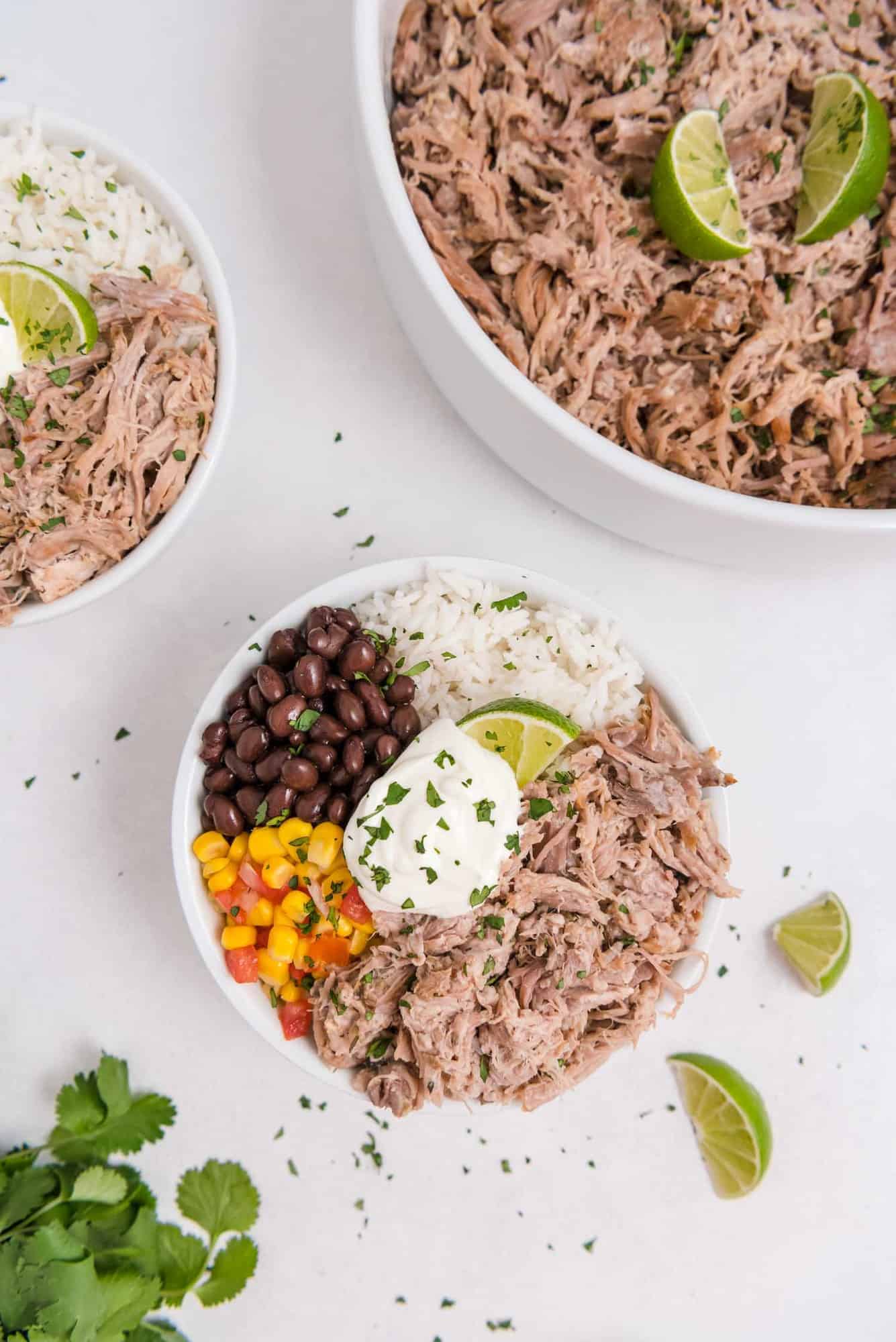 Overhead view of a burrito bowl, with a larger bowl of pork next to it.