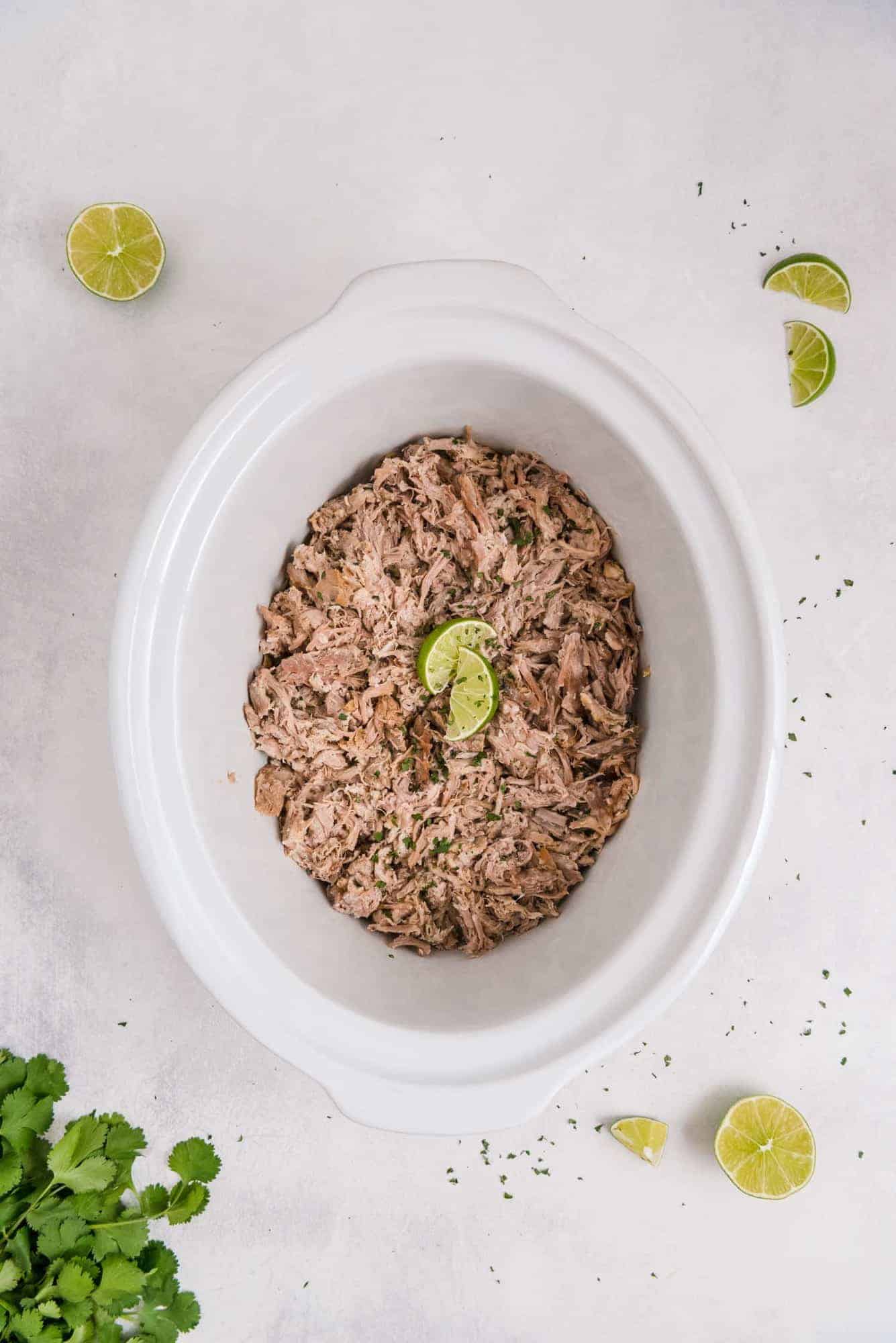 Pulled pork in a white crock pot.