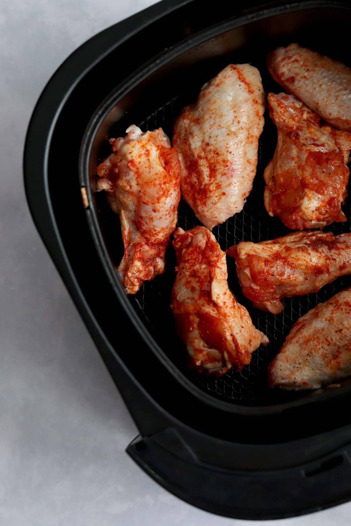 Uncooked wings in air fryer.