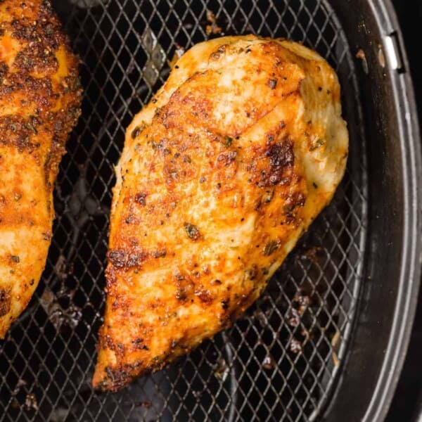 Cooked chicken breast in the basket of an air fryer.