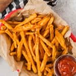 Red basket full of air fryer sweet potato fries, with a small container of ketchup