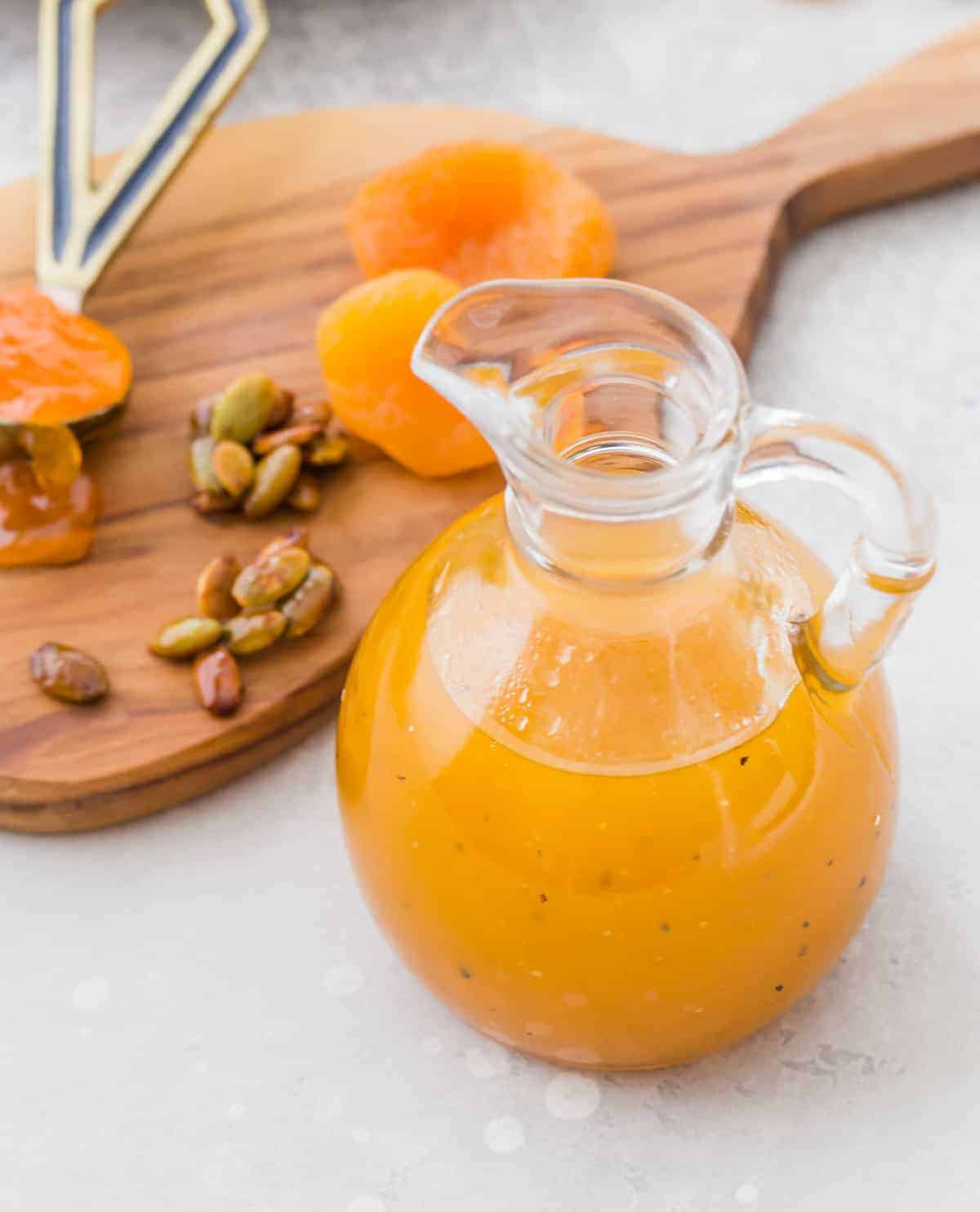 Dressing in a glass bottle, apricots and pepitas in the background.