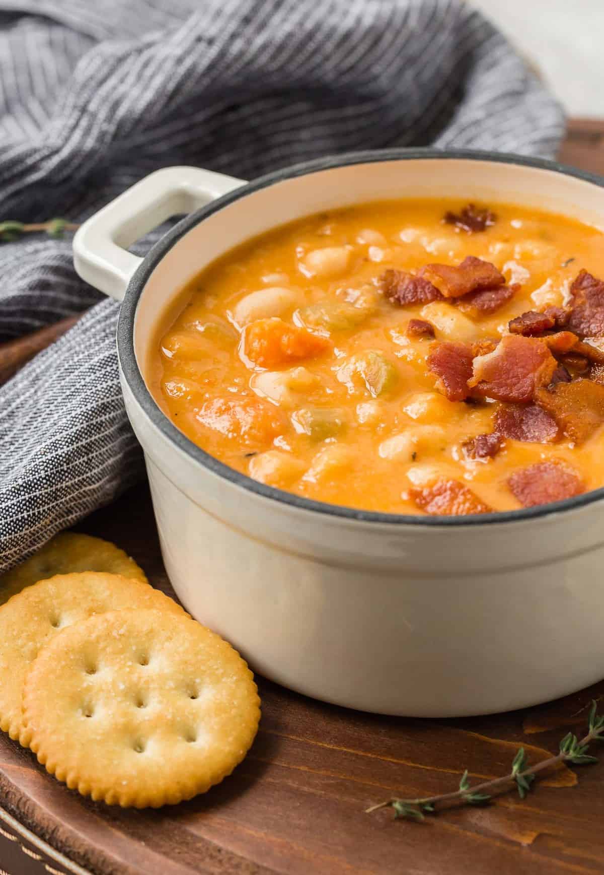 Bean soup on a tray with crackers and fresh thyme.