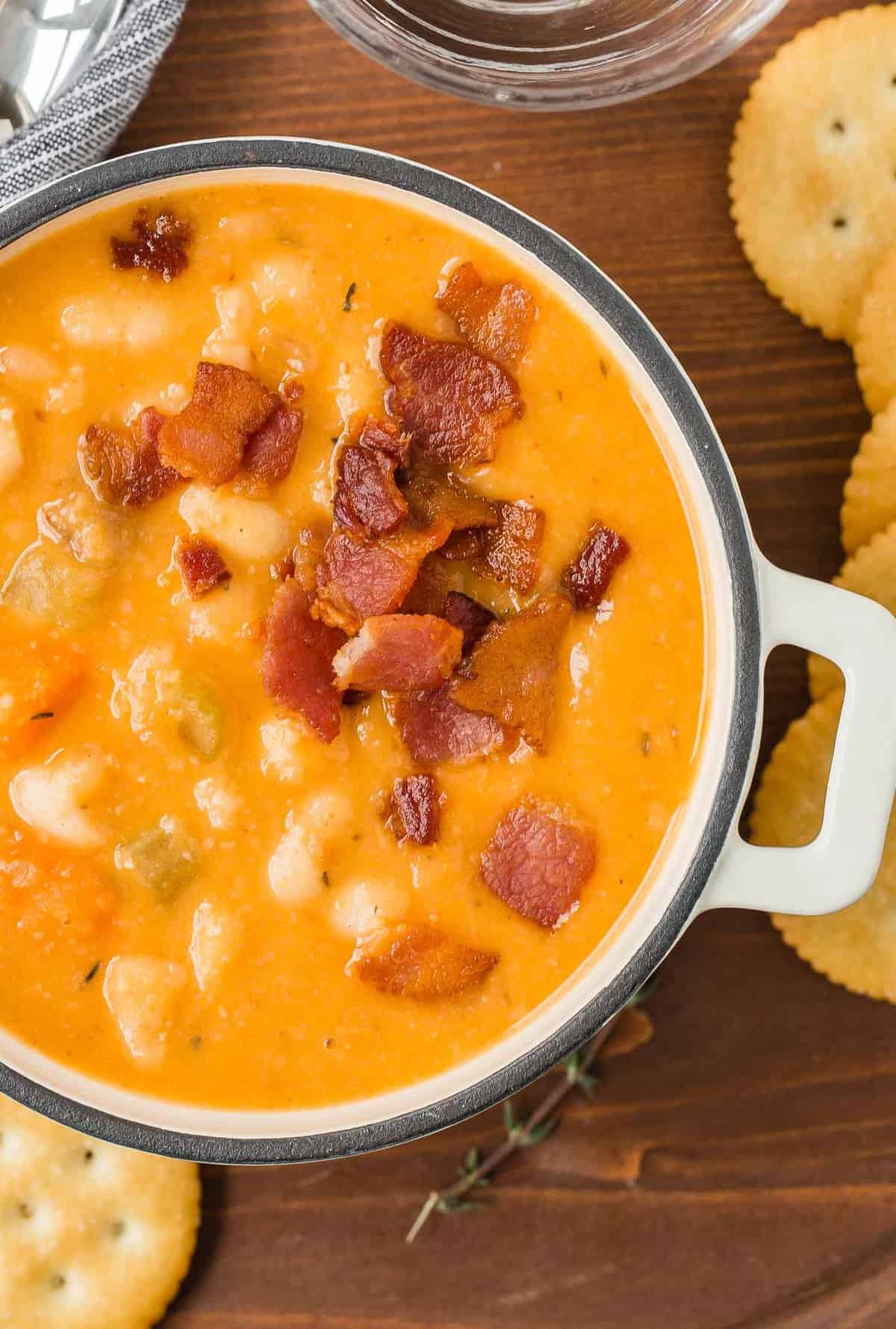 Close up view of bean and bacon soup with ritz crackers on a tray.