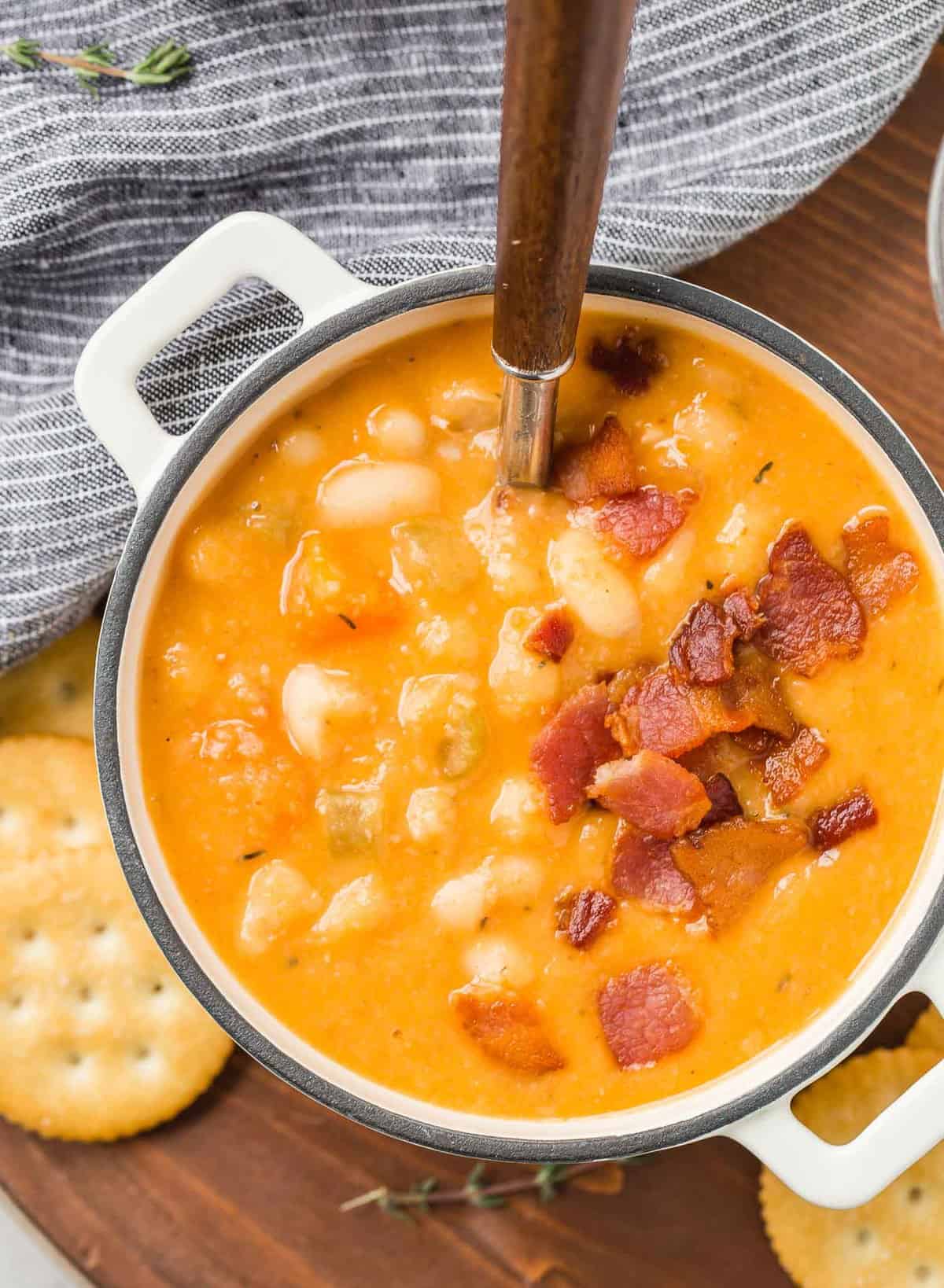 Overhead view of orange colored bean soup topped with crumbled bacon.