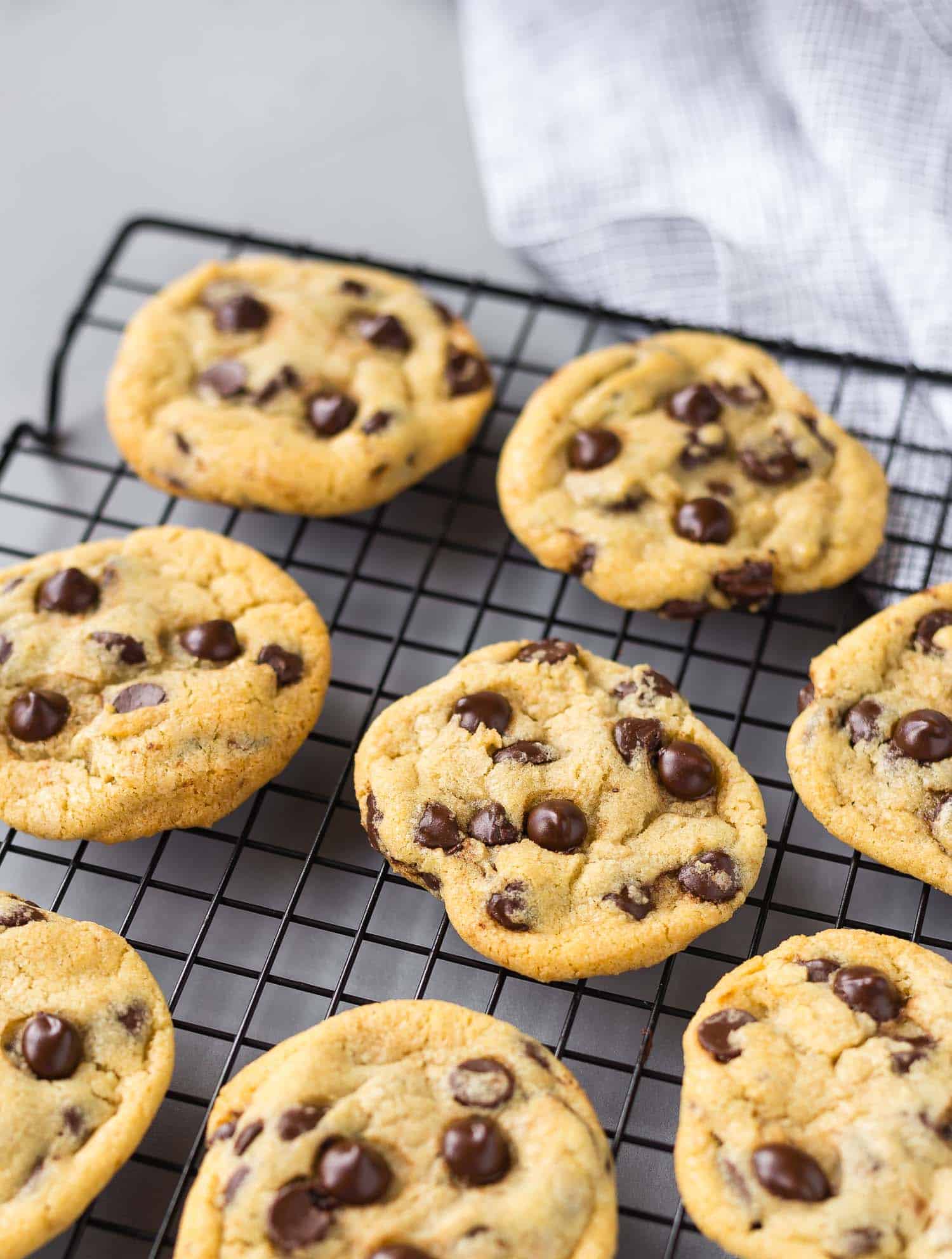 Cookies studded with chocolate chips on a cooling rack.