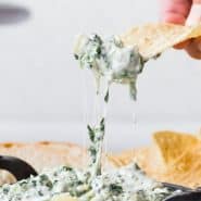 Spinach dip in a black dish, text overlay reads "crockpot spinach artichoke dip, rachelcooks.com"