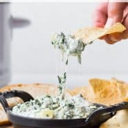 Spinach dip in a black dish, text overlay reads "crockpot spinach artichoke dip, rachelcooks.com"