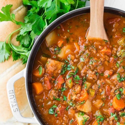 Overhead view of hamburger soup with potatoes, tomatoes, and vegetables.