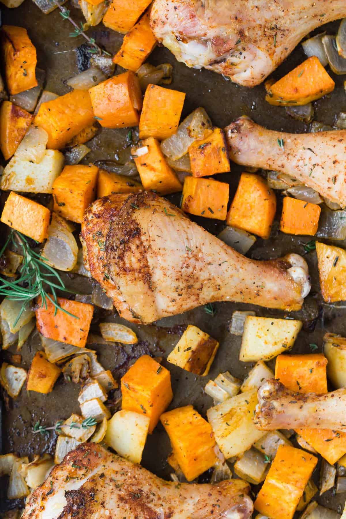 Chicken drumsticks on a sheet pan with potatoes.