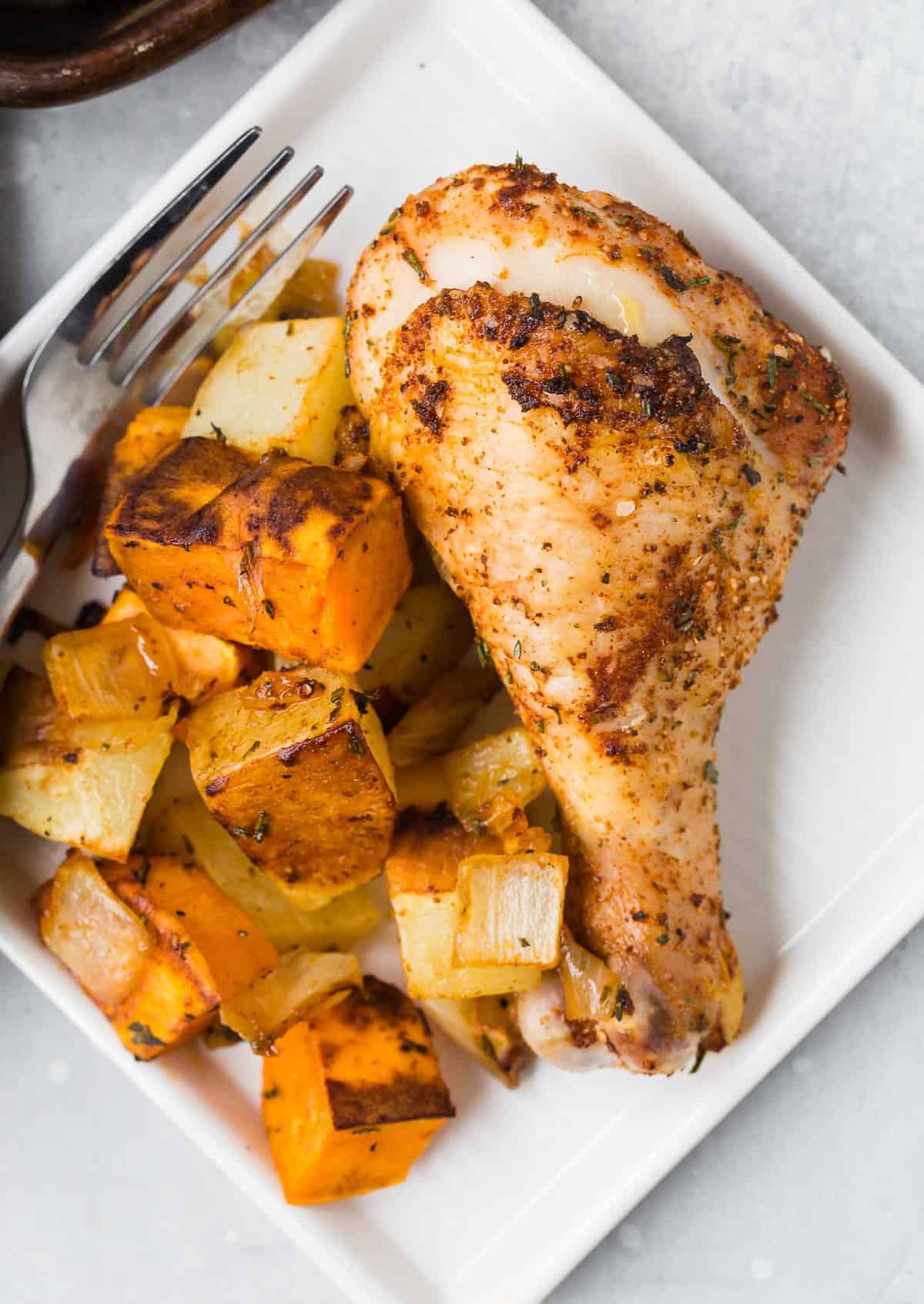 Chicken drumstick and roasted potatoes on a plate.