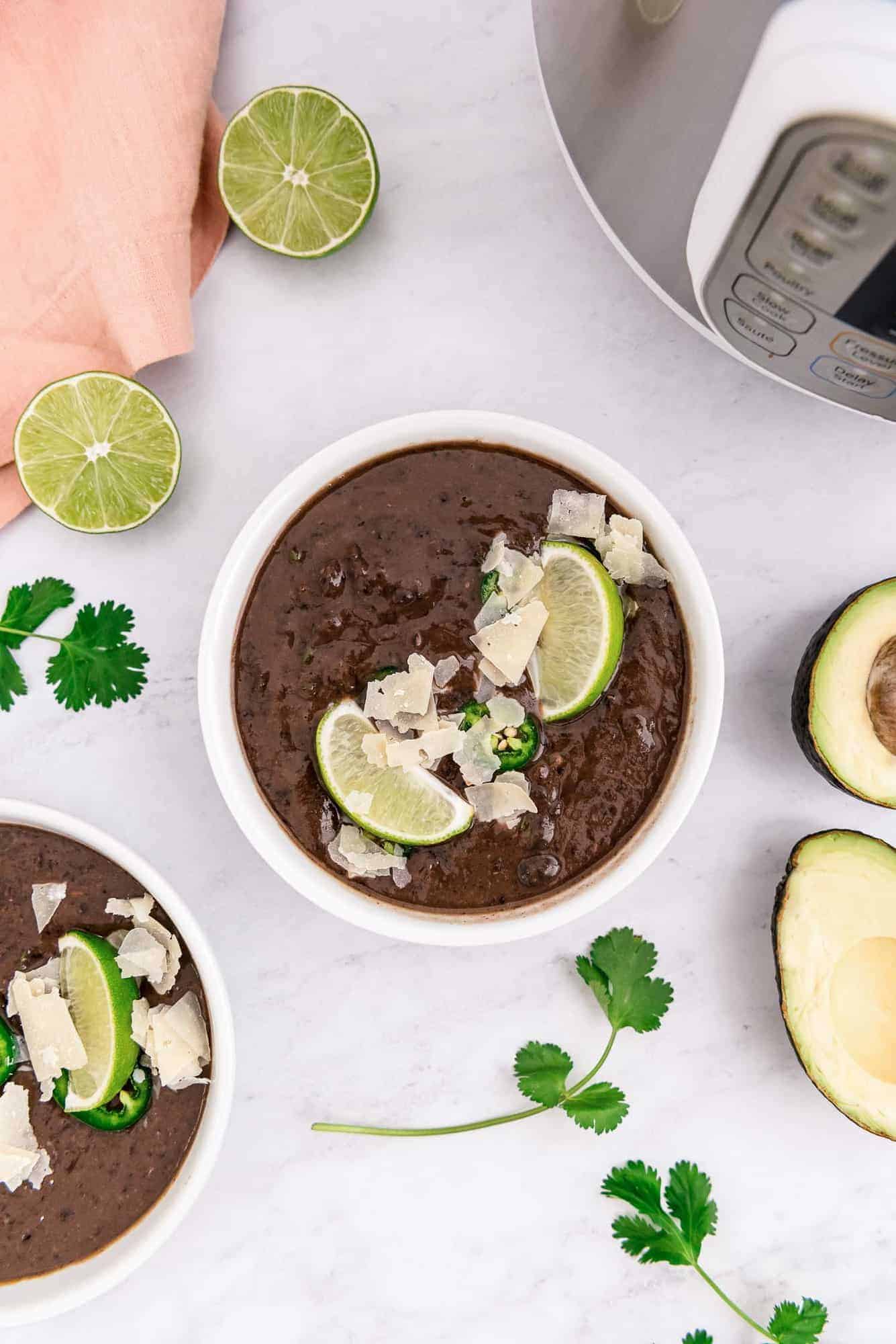 Dark brown soup in a bow, one more bowl partially visible, garnishes all around.