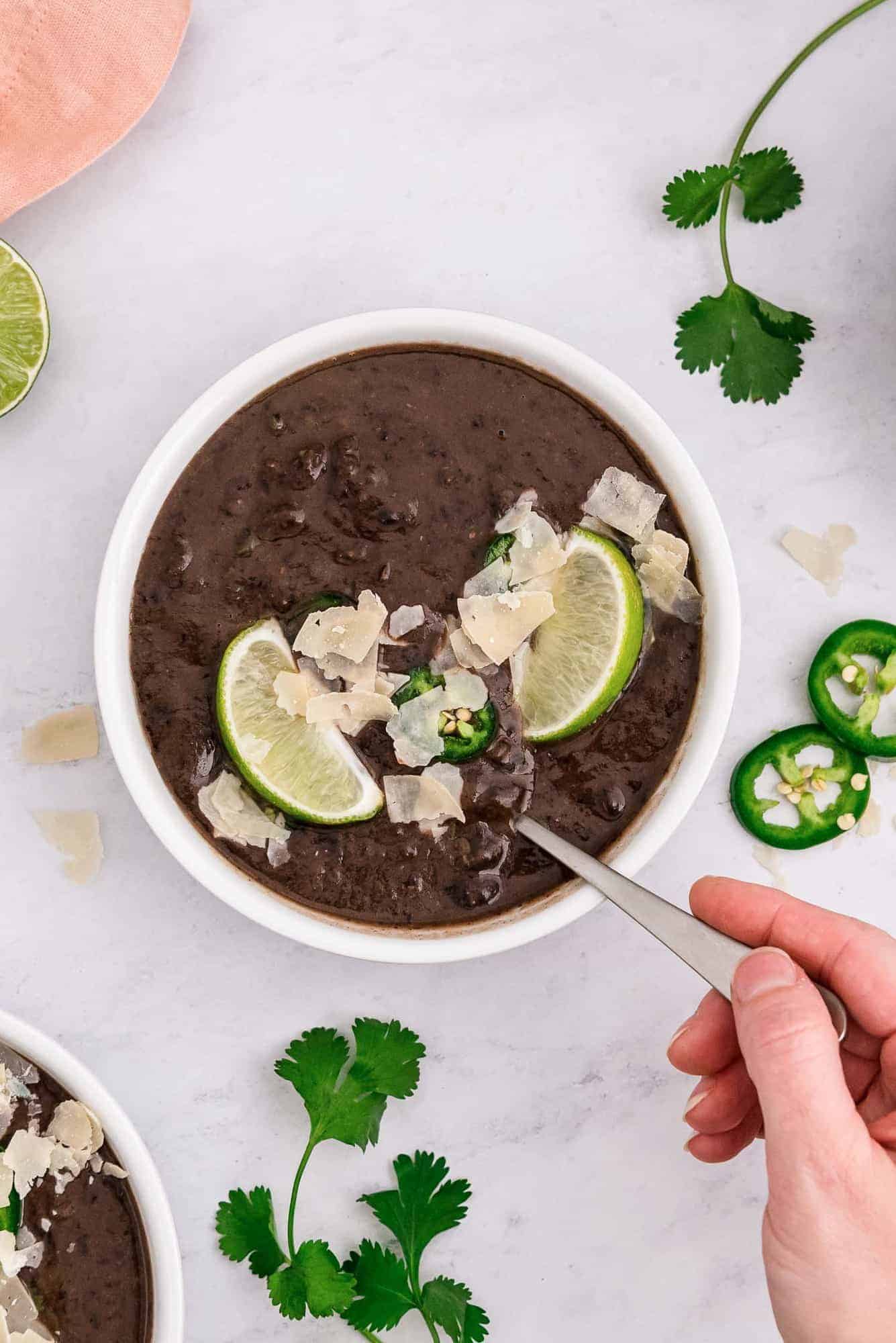 A hand holding a spoon in a bowl of soup.