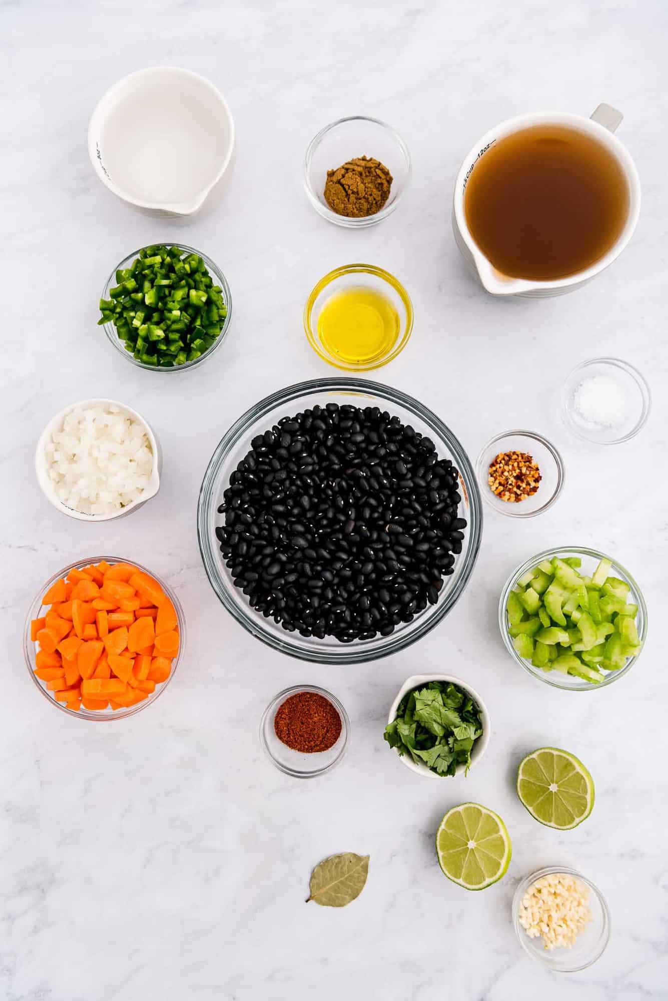 Overhead view of colorful ingredients in glass bowls, including black beans, carrots, jalapeno, and more.