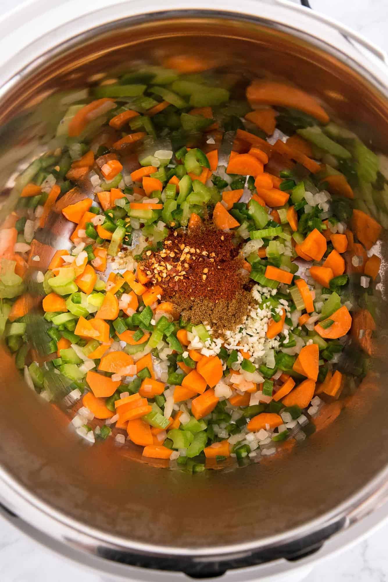 Ingredients in an instant pot, vegetables and spices included.