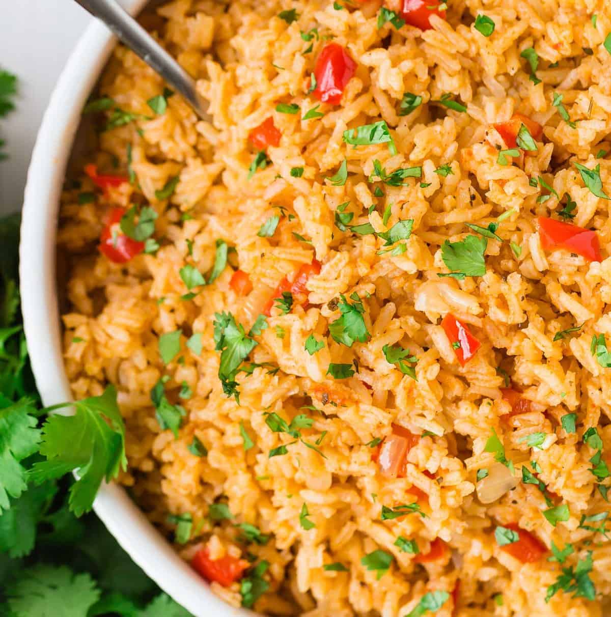 Close up of rice cooked with red peppers, onions, tomato paste, and spices.