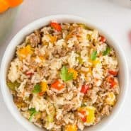 Sausage and rice in a white bowl, text overlay reads "one pan sausage, rice, and peppers, rachelcooks.com"