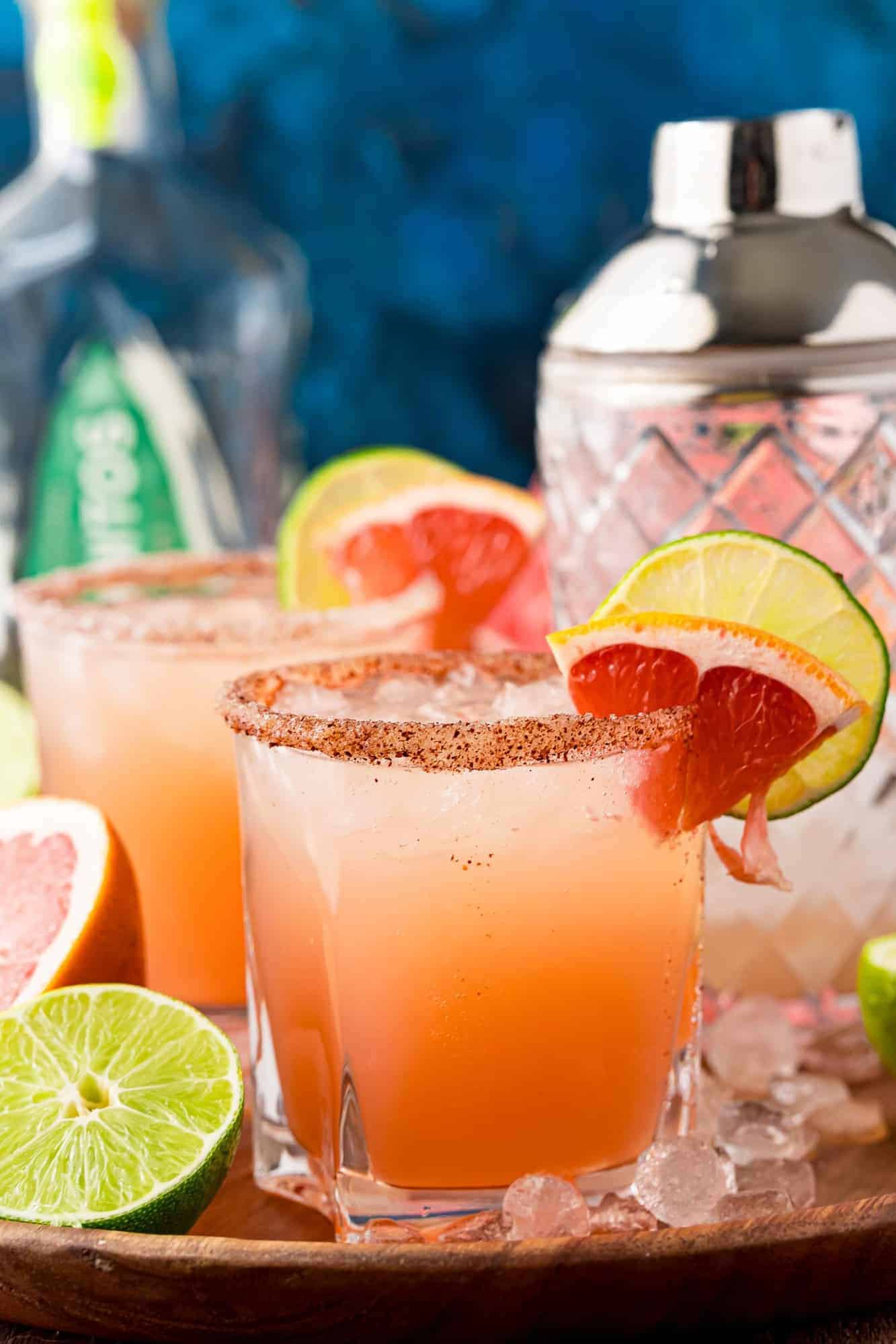 Paloma cocktails garnished with a wedge of watermelon. Blue backdrop.
