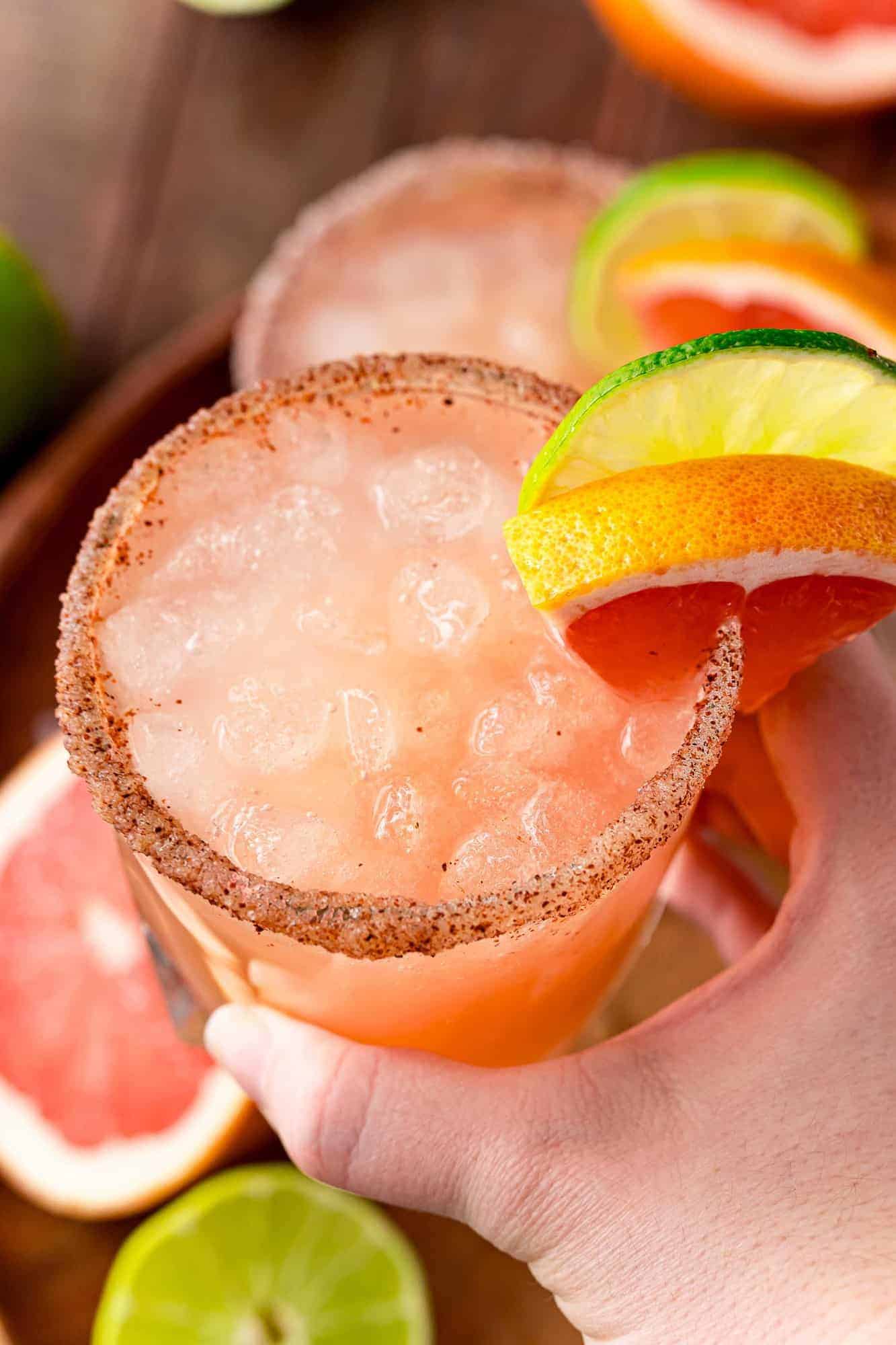 Grapefruit cocktail on ice, being held in a hand.