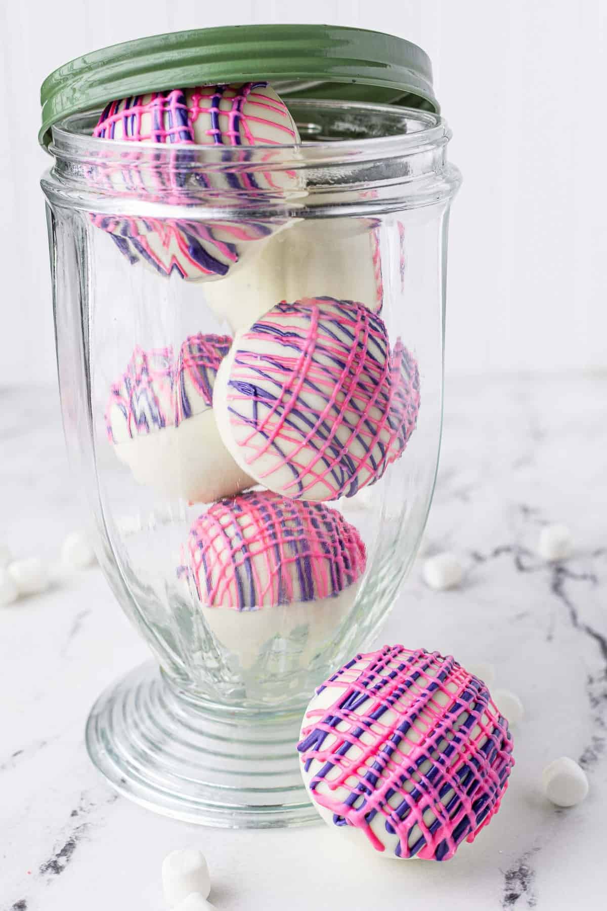 Hot chocolate bombs made with white chocolate, in a decorative jar.