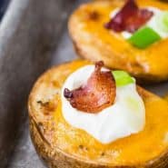 Potato slices on a baking sheet, text overlay reads "shortcut loaded potato skins, rachelcooks.com"