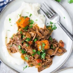 Overhead view of Italian pot roast on a plate, served over mashed potatoes.