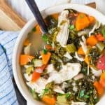 Colorful bowl of soup with chicken, kale, carrots.