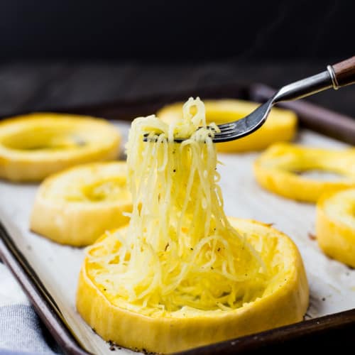 Ring of spaghetti squash, strands being pulled out with a fork.