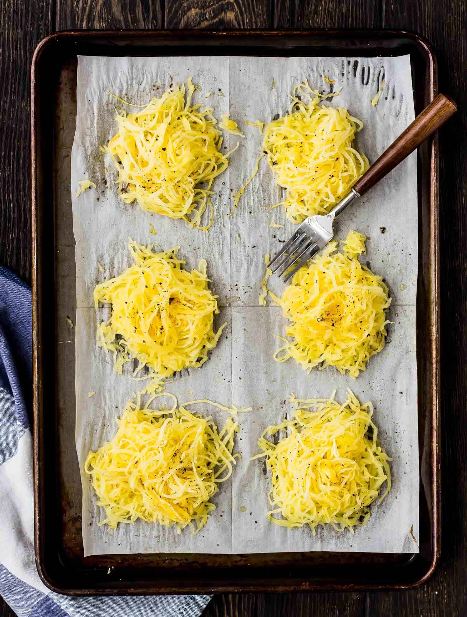 Piles of yellow spaghetti squash on a baking sheet lined with parchment.