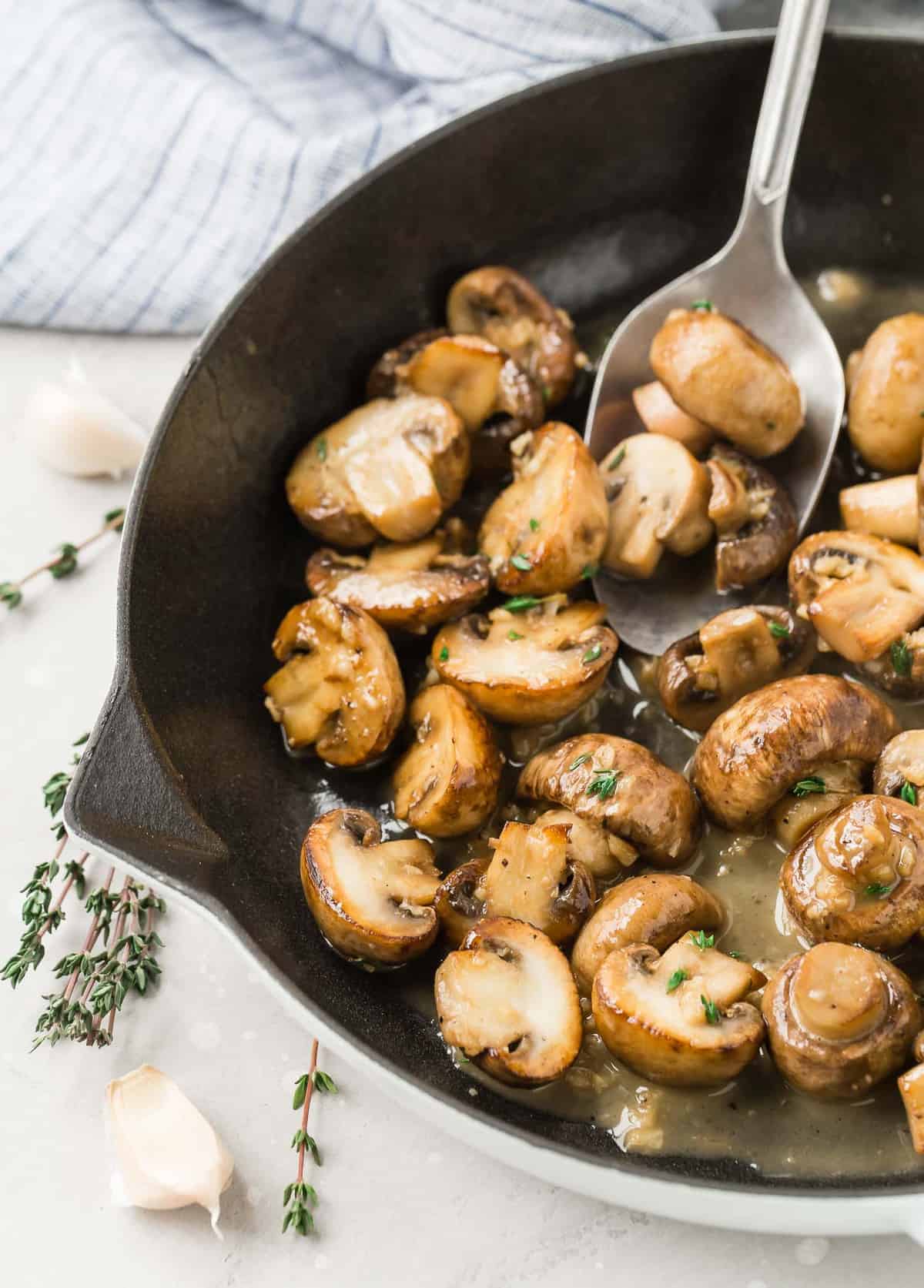 Mushrooms in a pan, a large spoon scooping them out.
