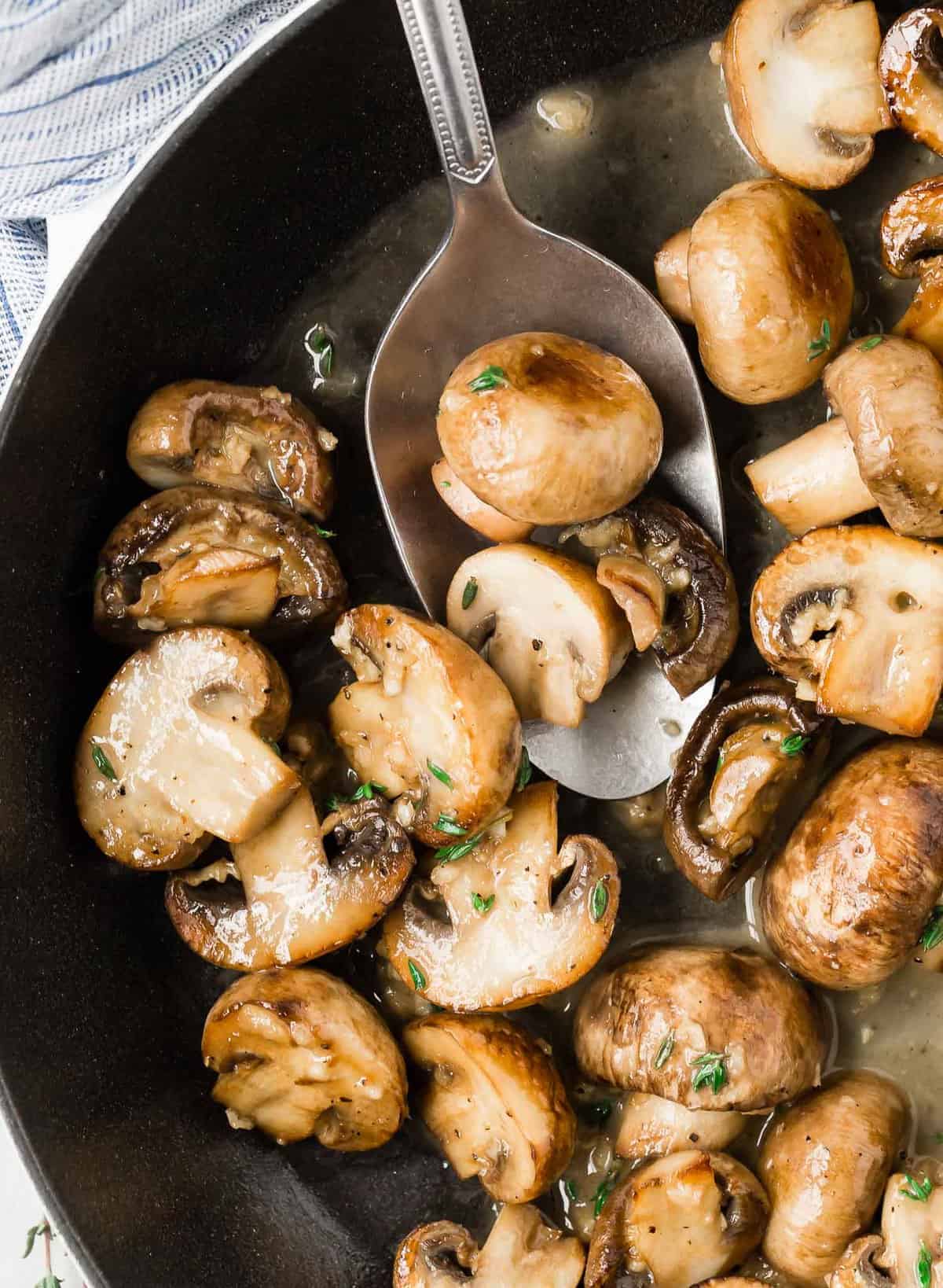 Mushrooms in a pan and on a silver spoon.