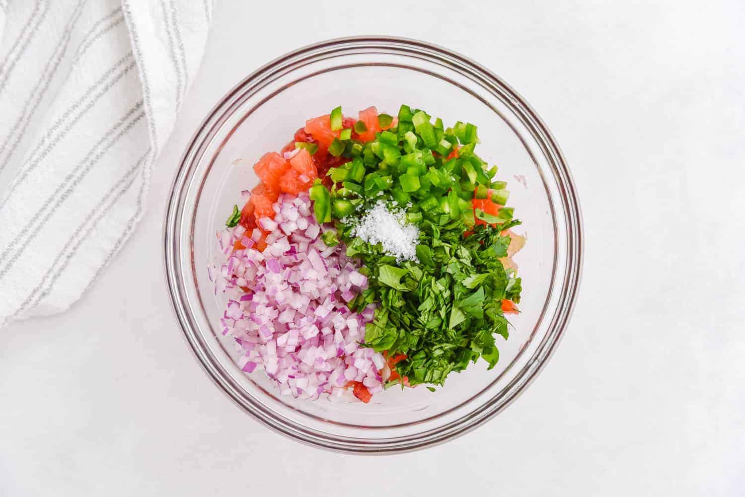 Salsa in a glass mixing bowl, not yet mixed together.