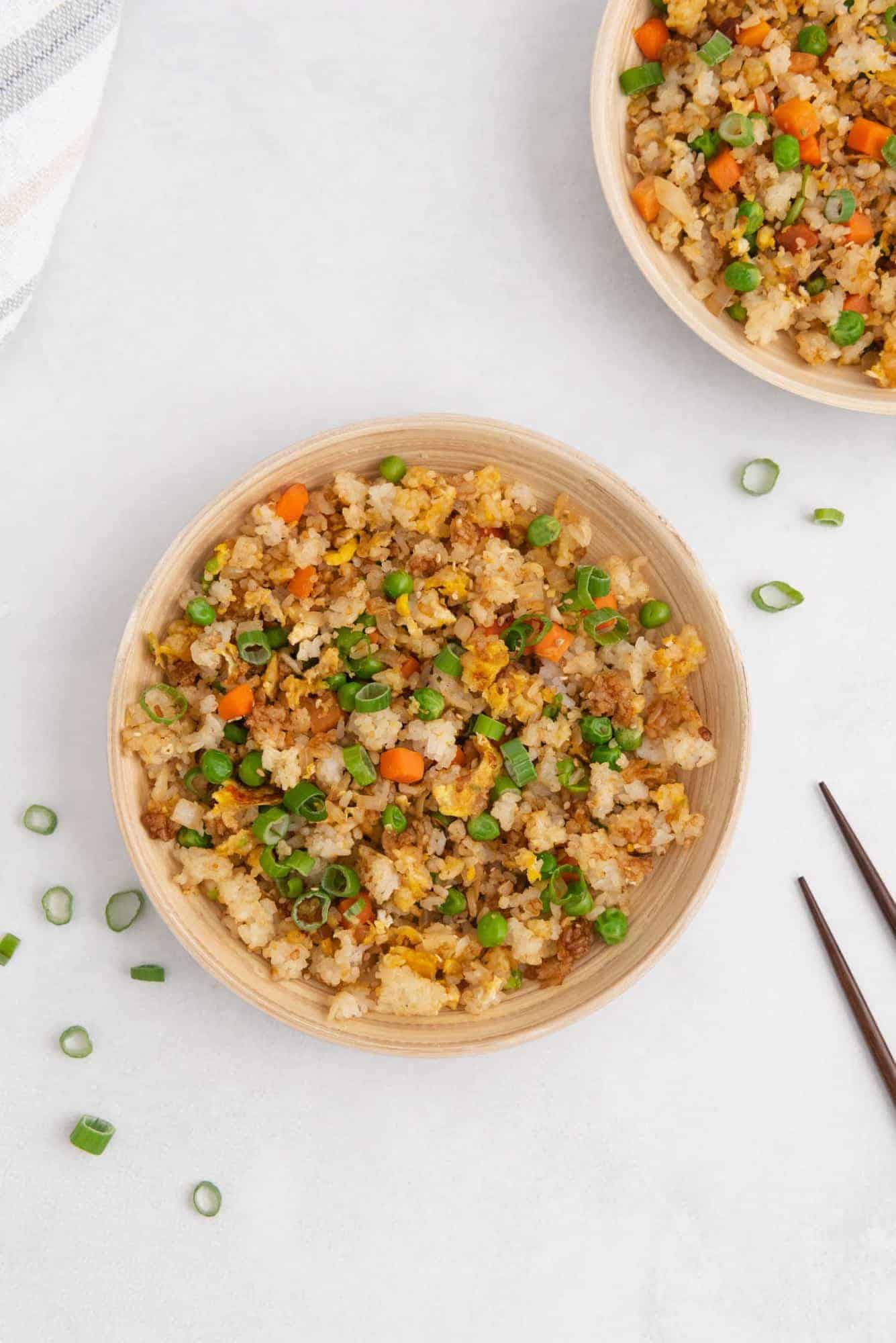 Two large plates of rice, eggs, and vegetables. Chopsticks partially visible. 