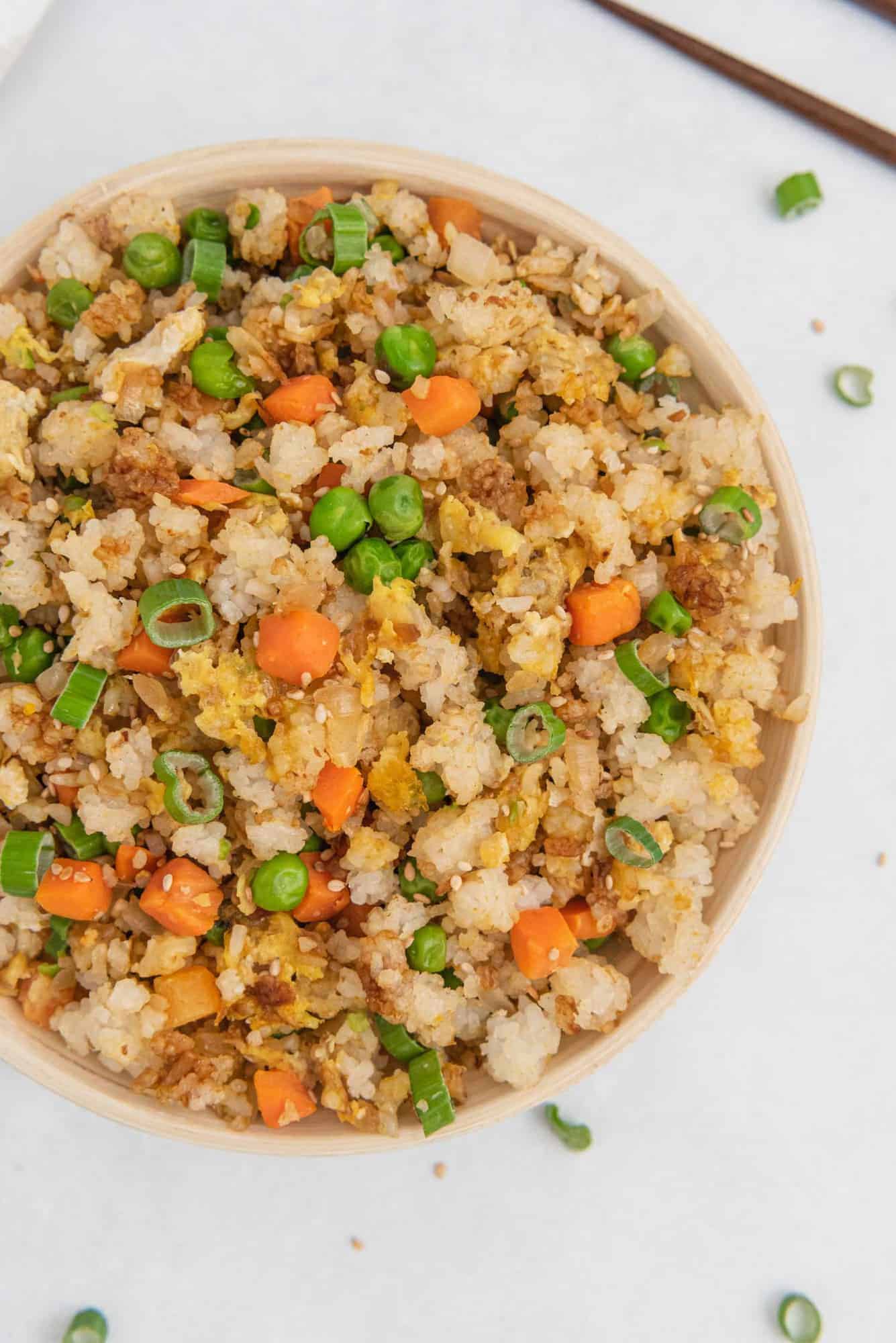 Overhead view of colorful fried rice in a round bowl on a white background.