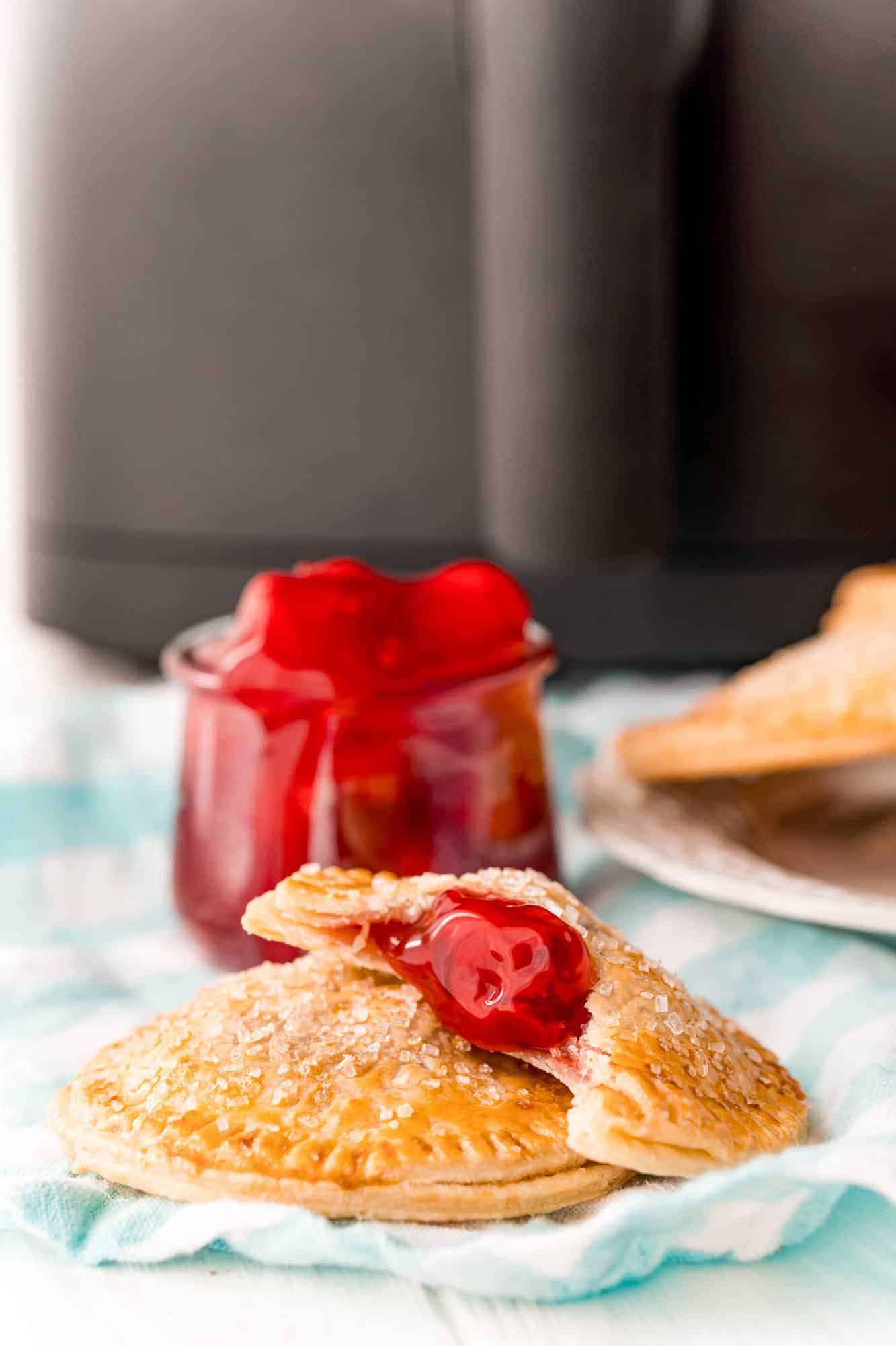 Cherry hand pies in front of an air fryer.