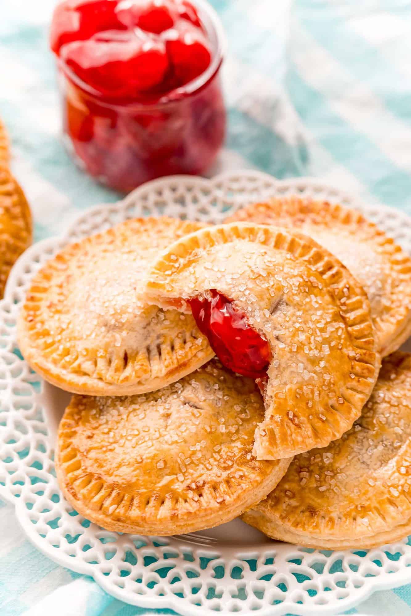 Pile of cherry hand pies on a decorative white plate.