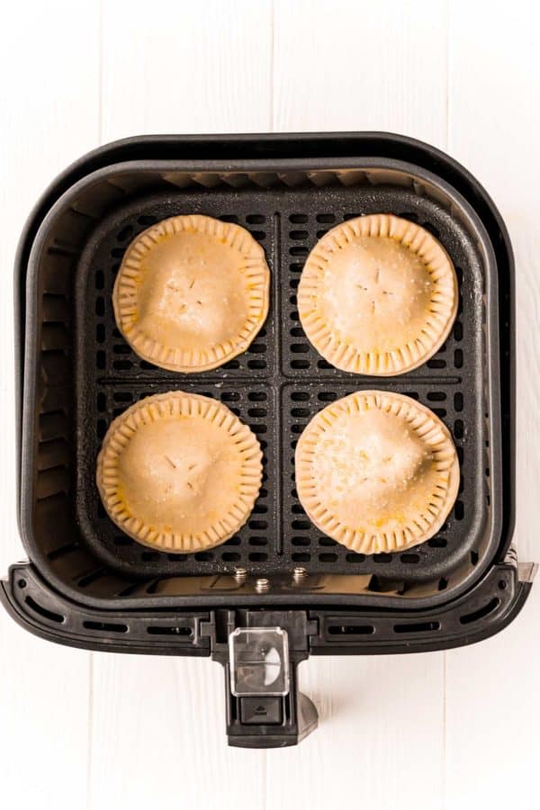 Uncooked hand pies in the basket of an air fryer.