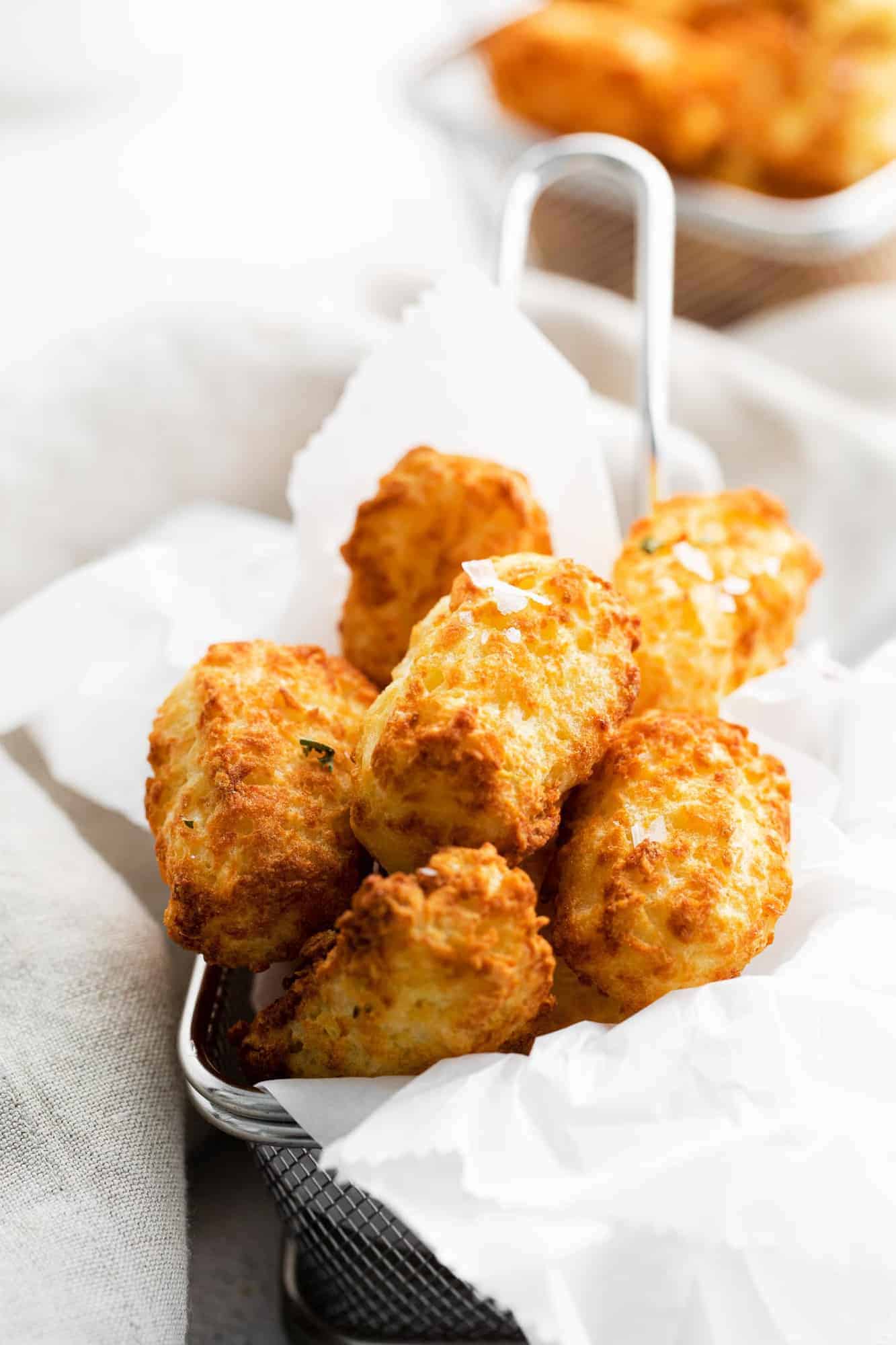 Close up of tater tots in a tiny fryer basket.