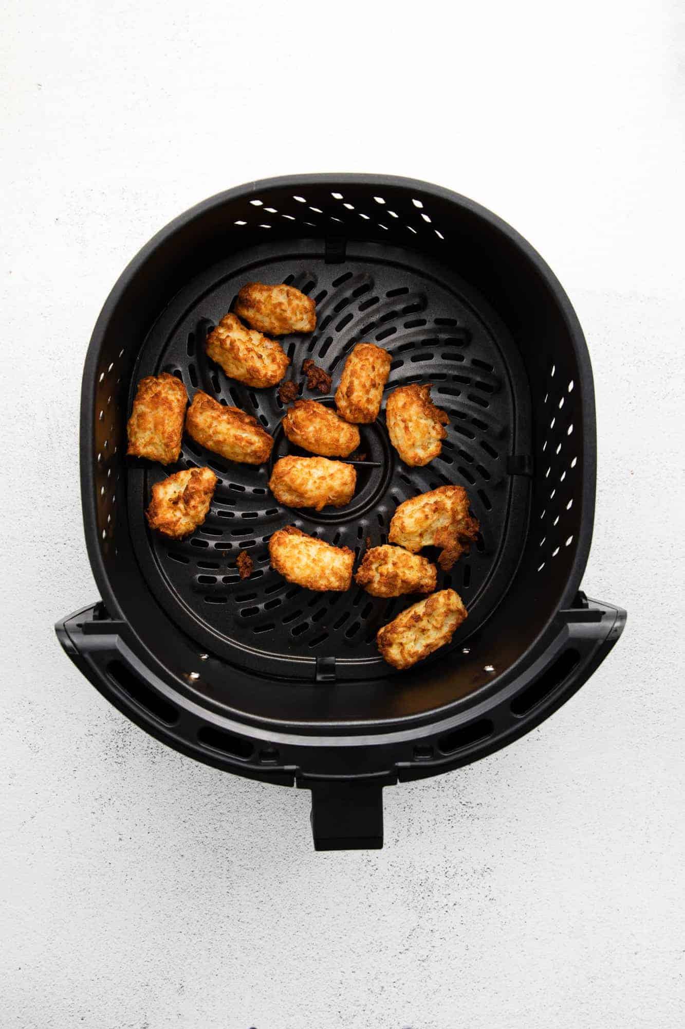 Cooked air fryer tater tots still in basket.