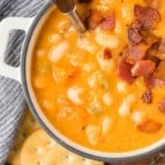 Bean soup topped with bacon in a small white bowl.