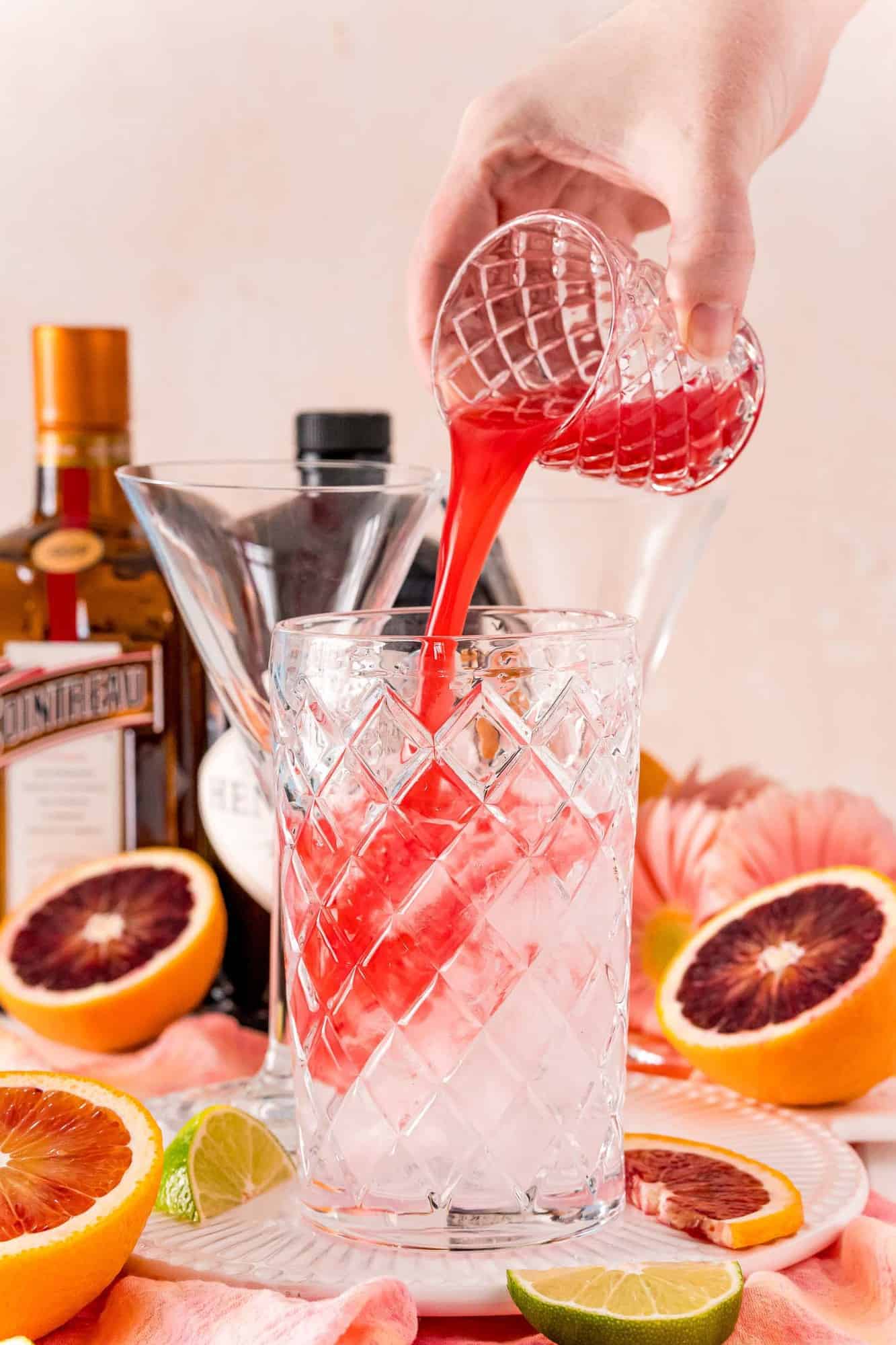 Blood orange juice being poured into a martini glass.