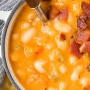 Soup in a white two-handled bowl, text overlay reads "homemade bean and bacon soup, rachelcooks.com"