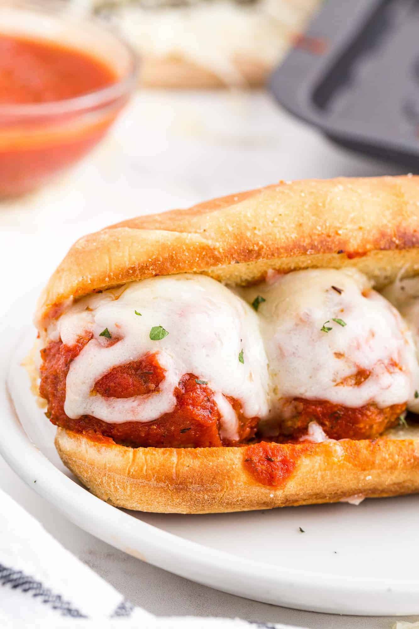 Close up of meatball sandwich, with sauce dripping over edge of bun.