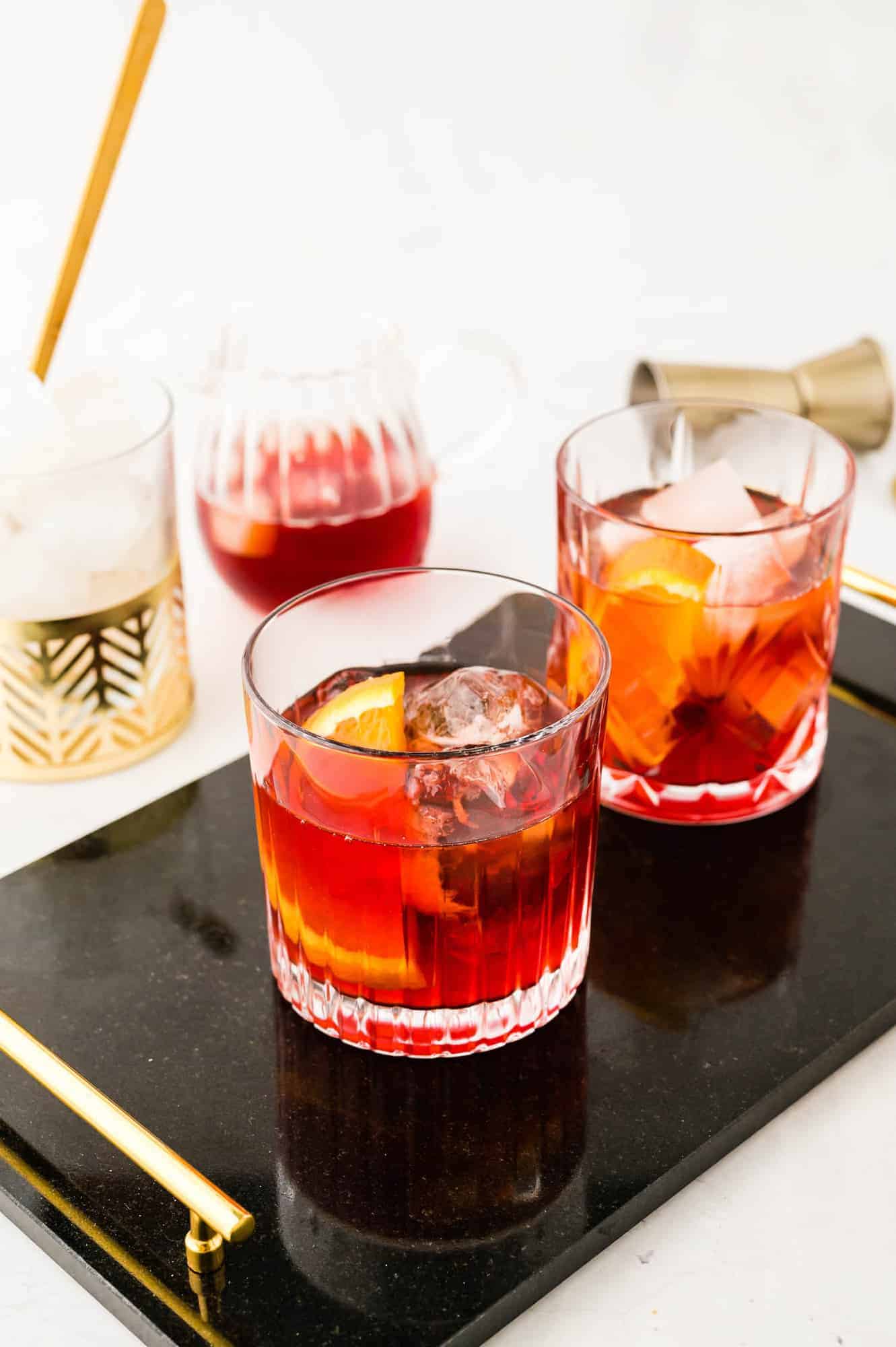Two cocktails on a black tray.